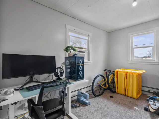 Carpeted office space with a baseboard heating unit