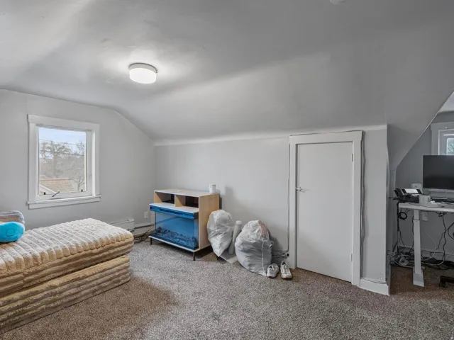 Bedroom featuring vaulted ceiling, carpet, and a desk