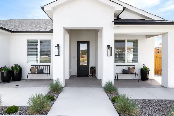 Doorway to property with stucco siding, roof with shingles, and a porch