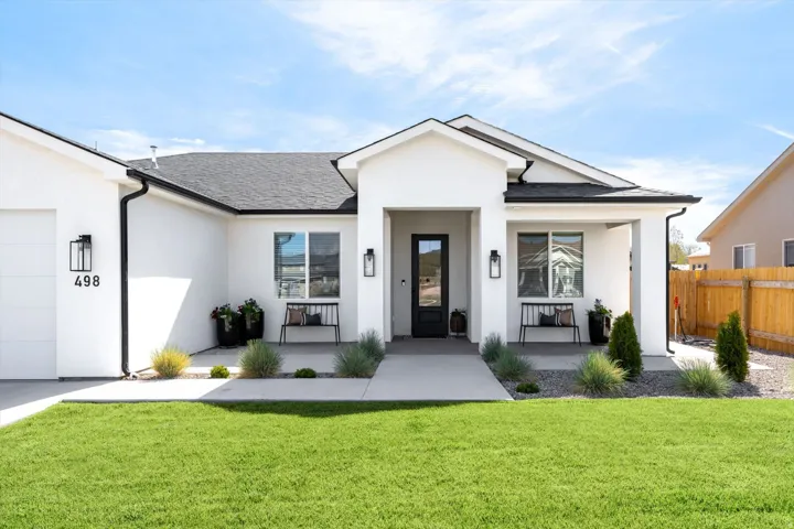 View of front facade with stucco siding, a shingled roof, and an attached garage