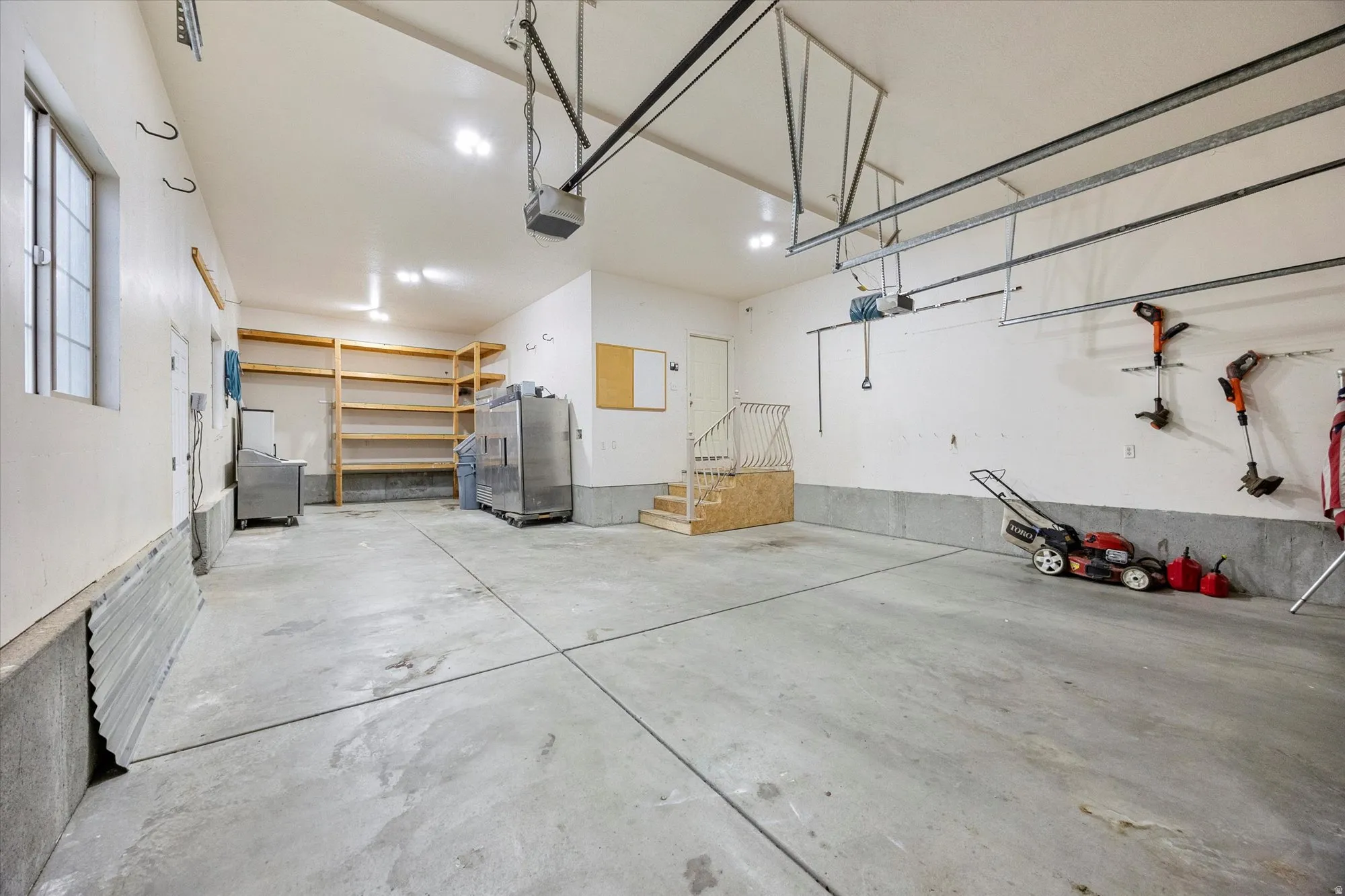 Garage with stainless steel fridge and a garage door opener