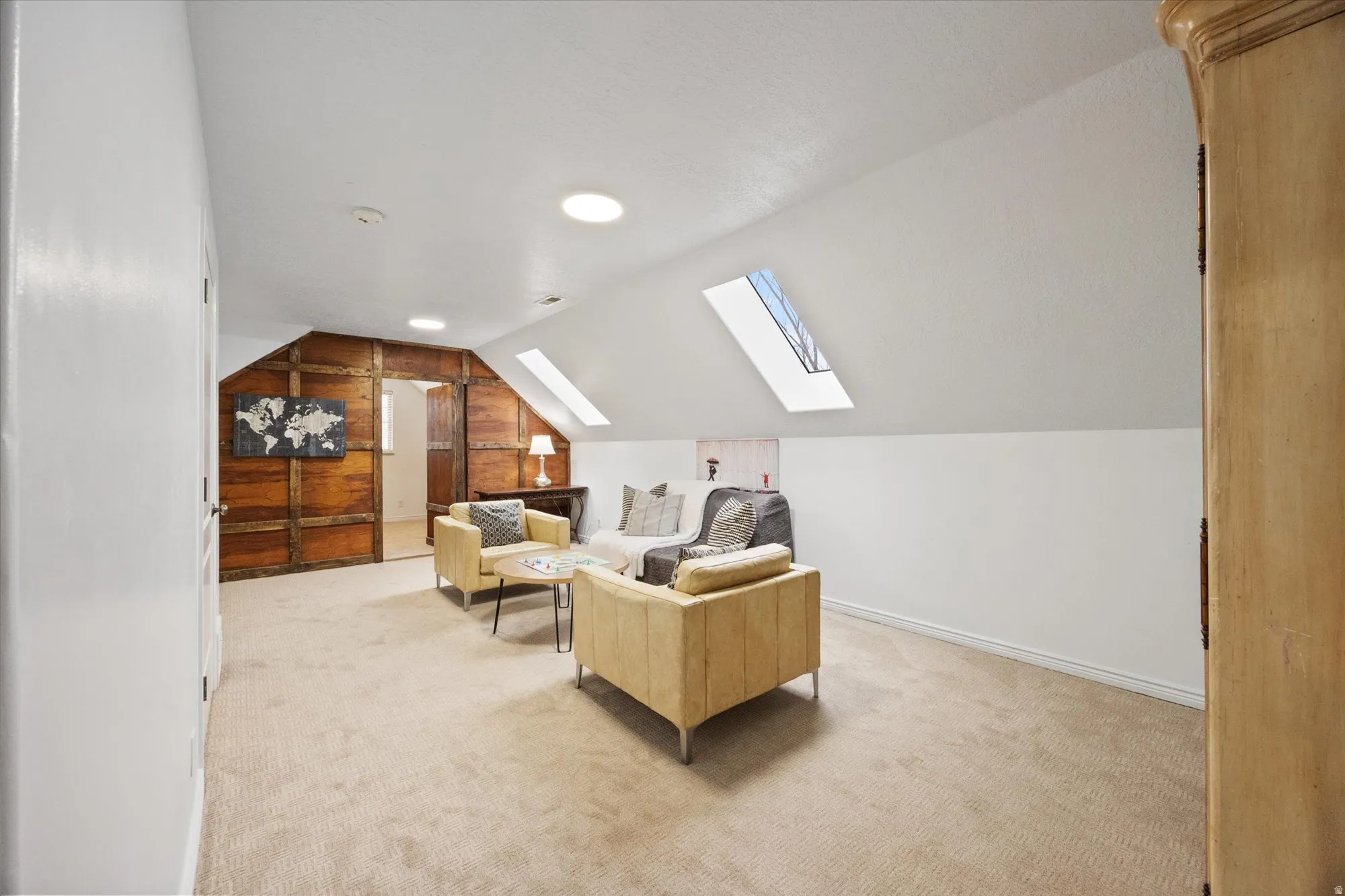 Living area with a skylight, vaulted ceiling, wood walls, and light colored carpet