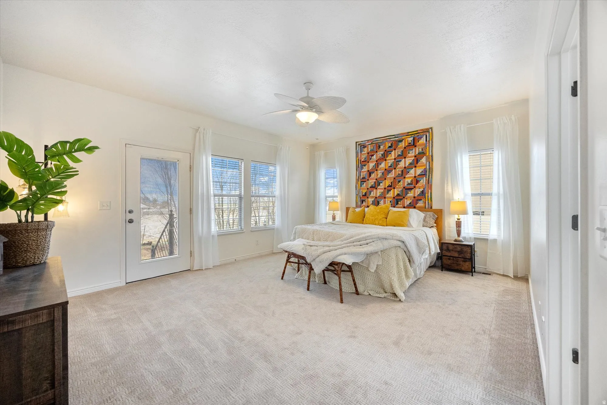Bedroom with access to exterior, multiple windows, light colored carpet, and ceiling fan