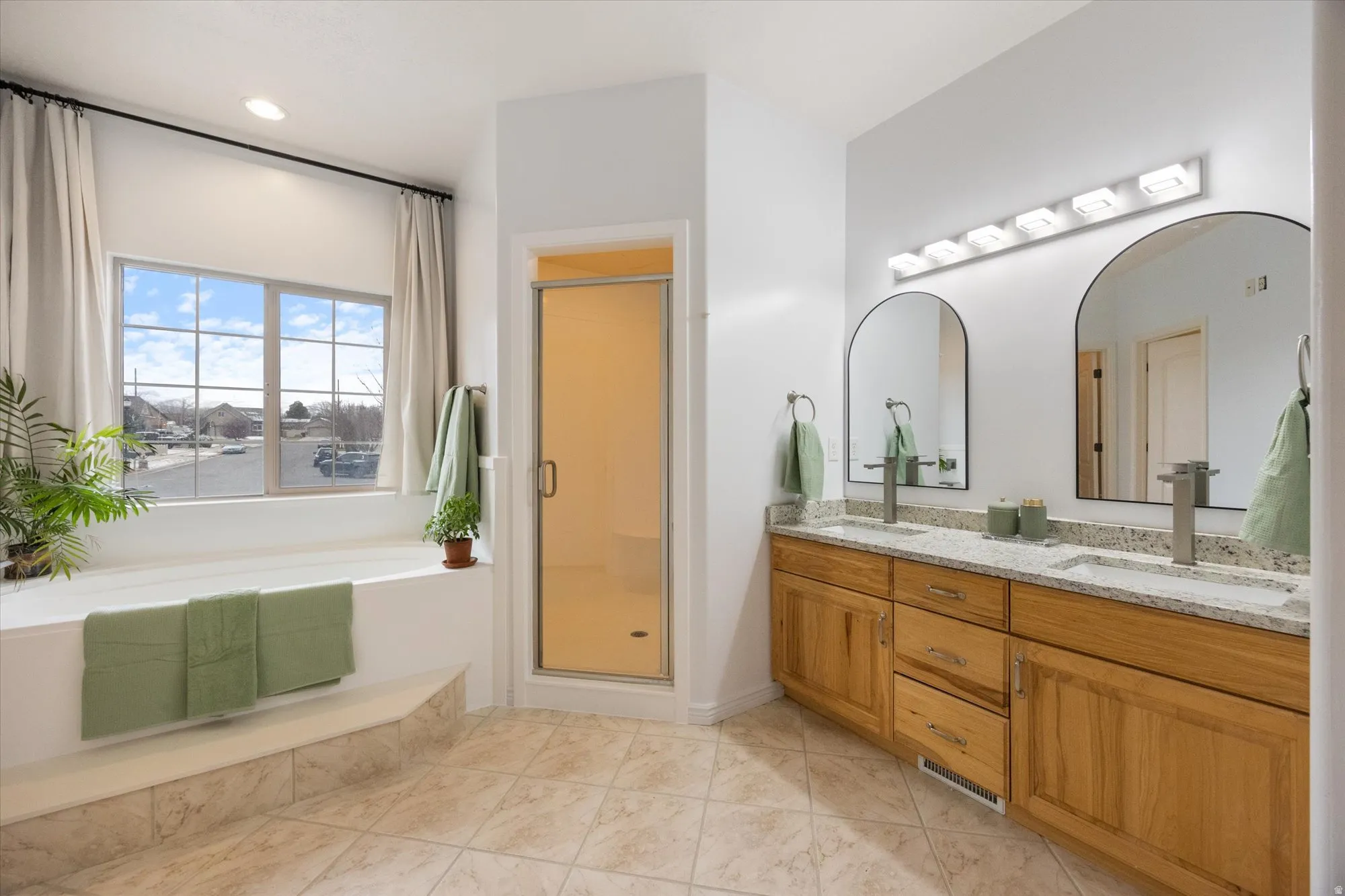 Full bathroom with double vanity, a stall shower, a bath, and light tile patterned flooring