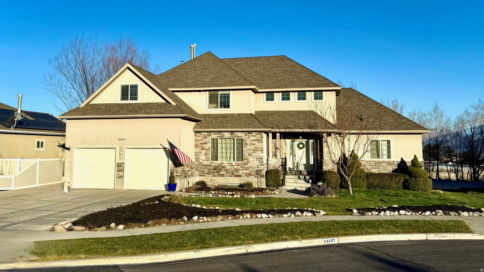 View of front of house featuring roof with shingles, stone siding, concrete driveway, stucco siding, and a garage