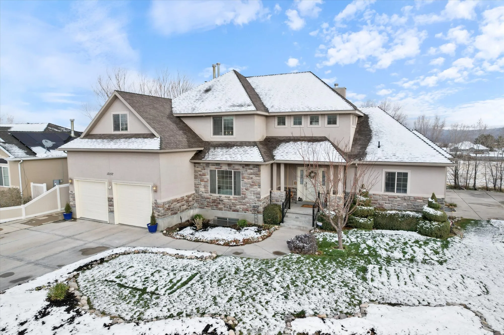 View of front facade featuring stone siding, stucco siding, concrete driveway, an attached garage, and a chimney