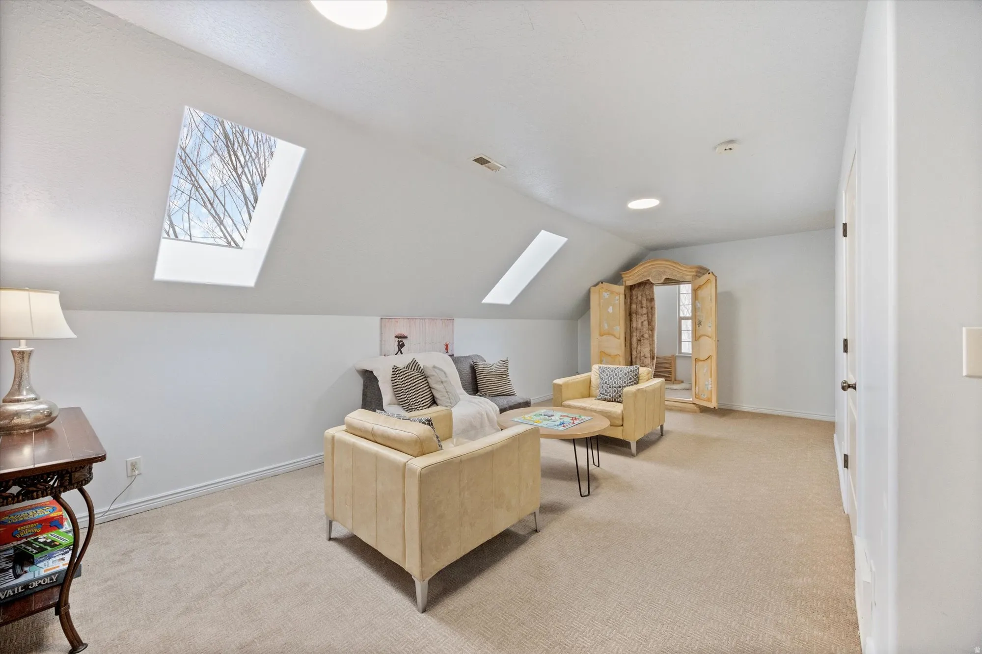 Living room featuring a skylight, lofted ceiling, and light carpet