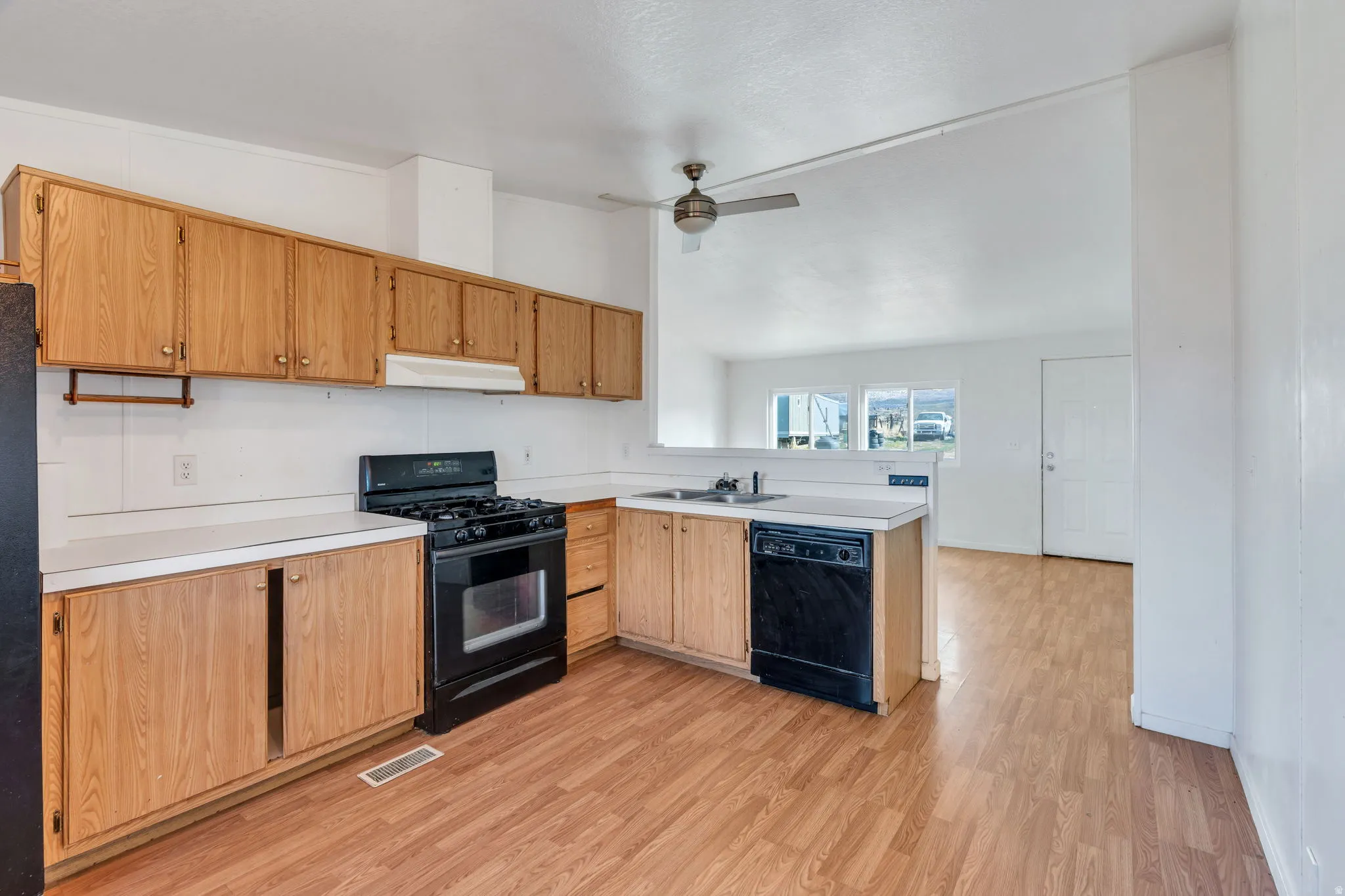 Kitchen featuring black appliances, vaulted ceiling, light countertops, a ceiling fan, and light wood-style floors