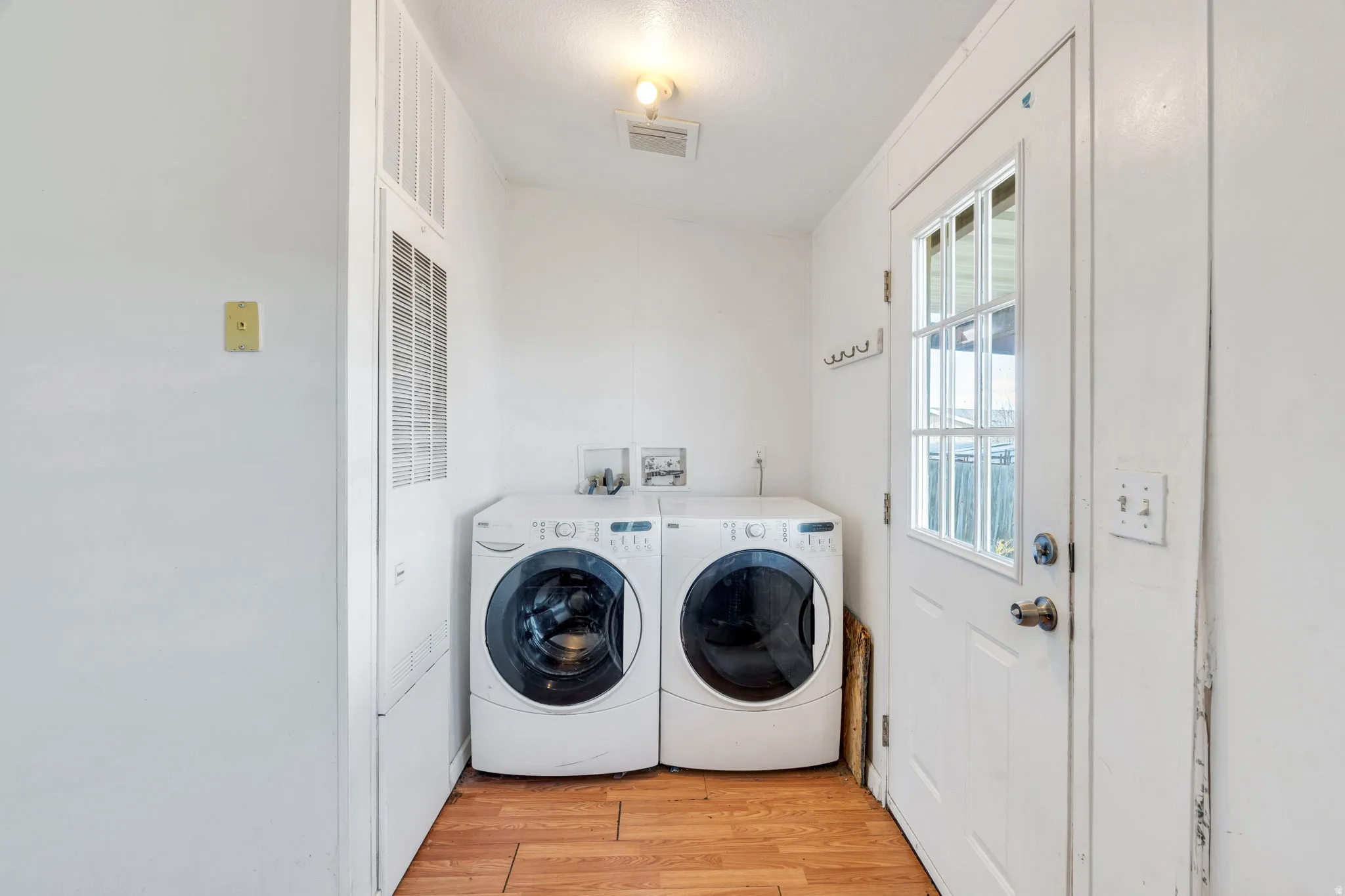 Washroom featuring light wood-style floors, a heating unit, and independent washer and dryer