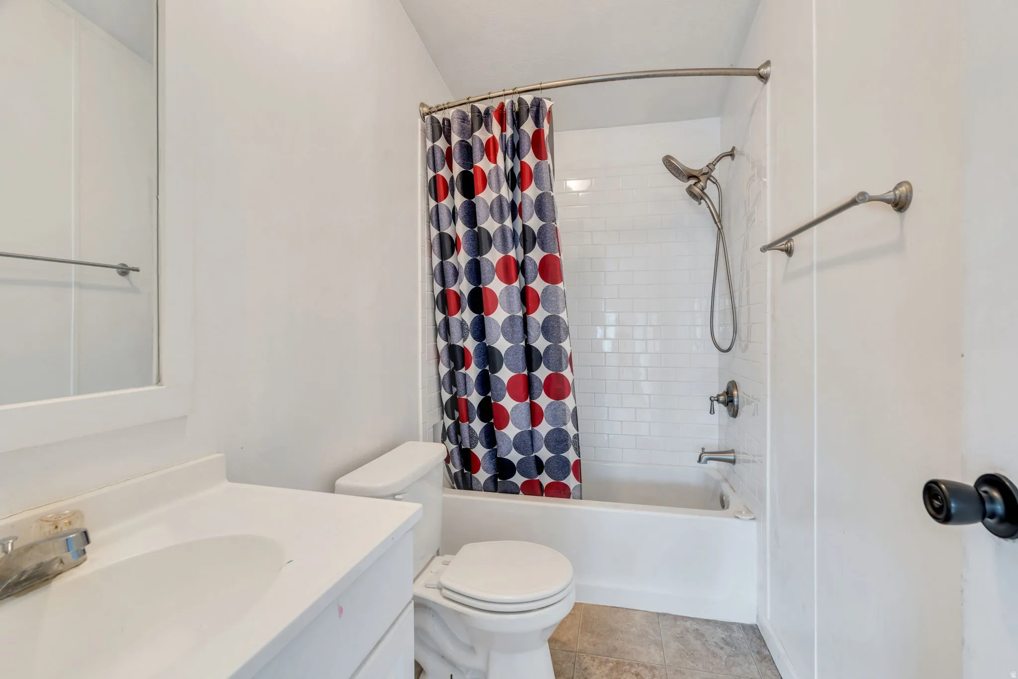 Full bath featuring shower / bath combo with shower curtain, vanity, and light tile patterned floors