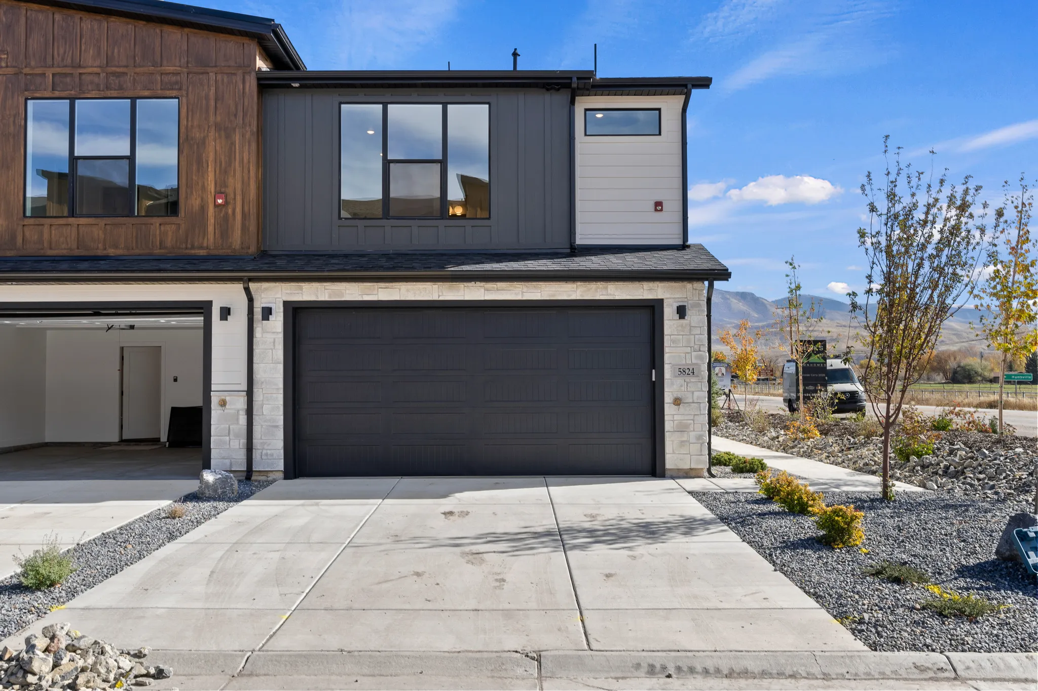 Contemporary house featuring stone siding, concrete driveway, a mountain view, and a garage