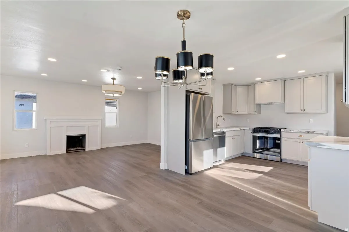 Kitchen with stainless steel appliances, light wood-style flooring, a chandelier, open floor plan, and recessed lighting