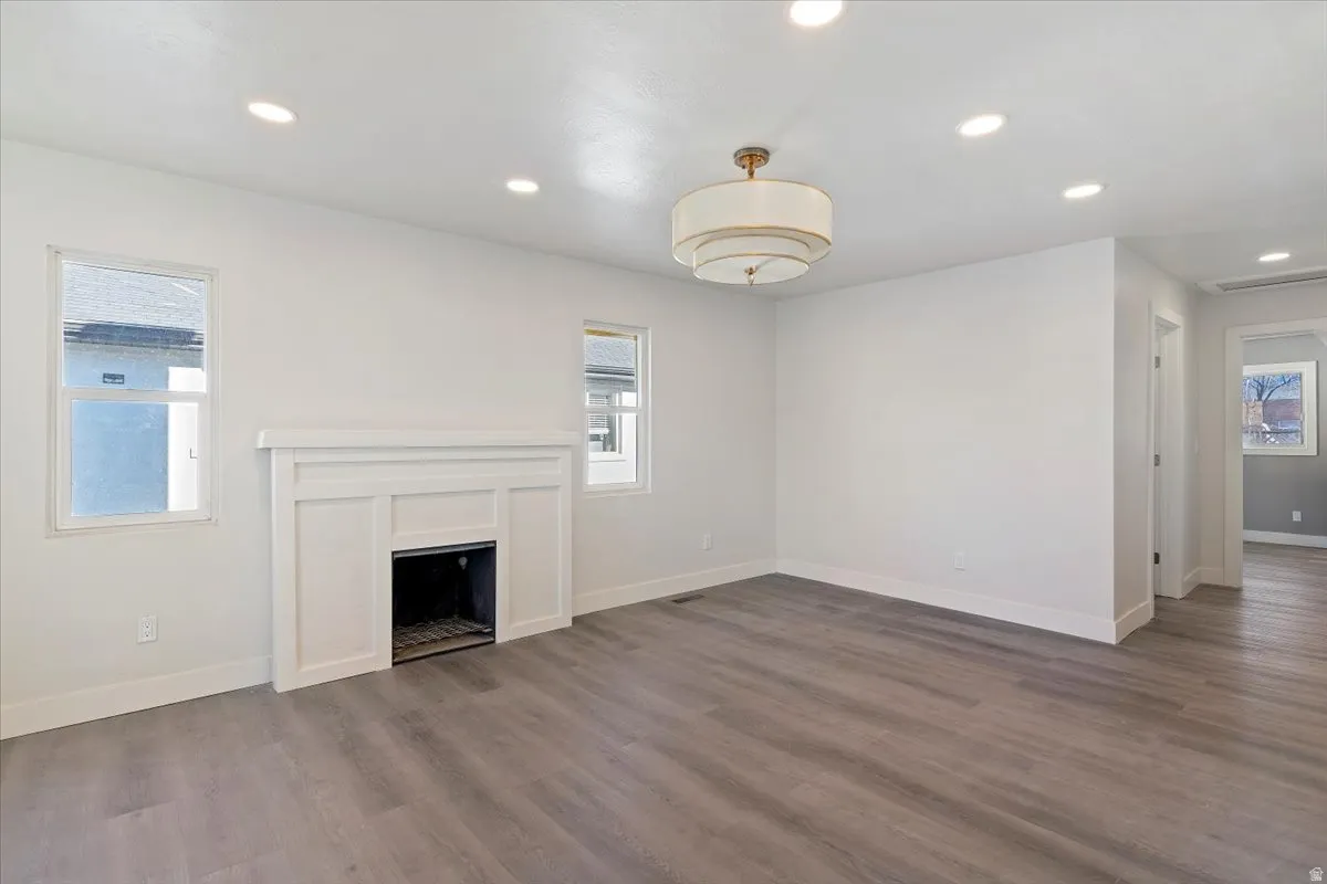 Unfurnished living room featuring plenty of natural light, a fireplace, recessed lighting, and wood finished floors