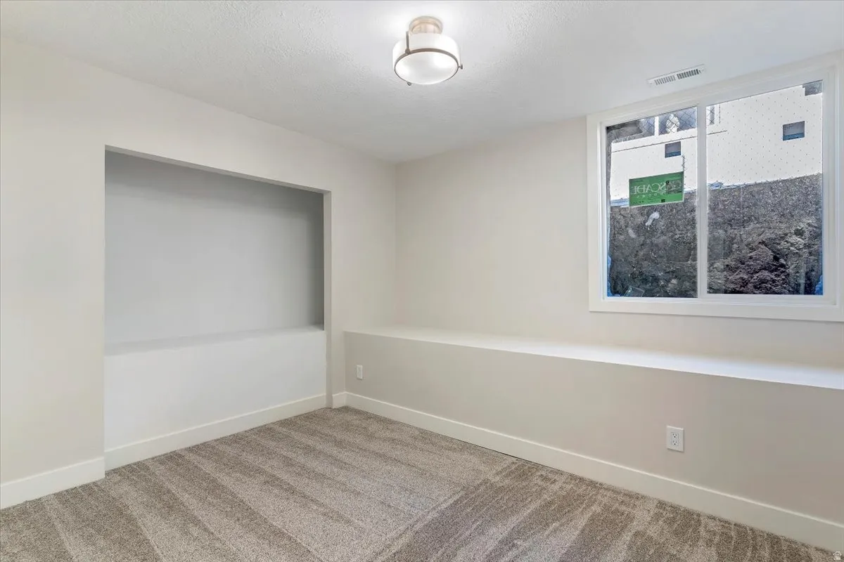 Carpeted spare room featuring baseboards and a textured ceiling