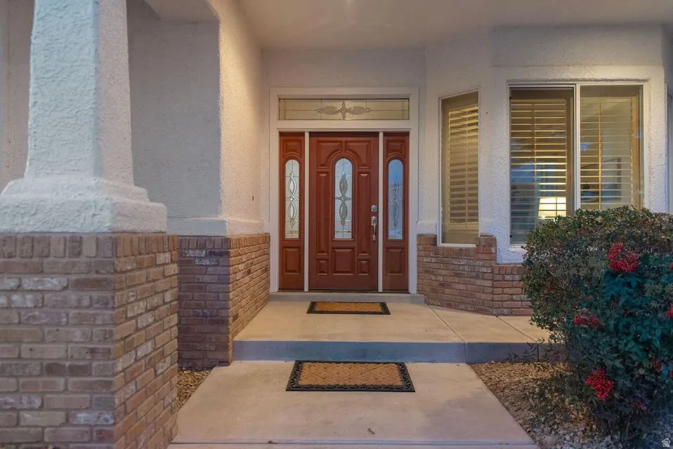 Property entrance with a porch, stucco siding, and brick siding