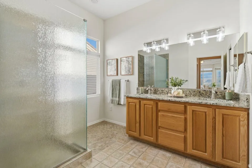 Bathroom featuring an enclosed shower, double vanity, and light tile patterned floors