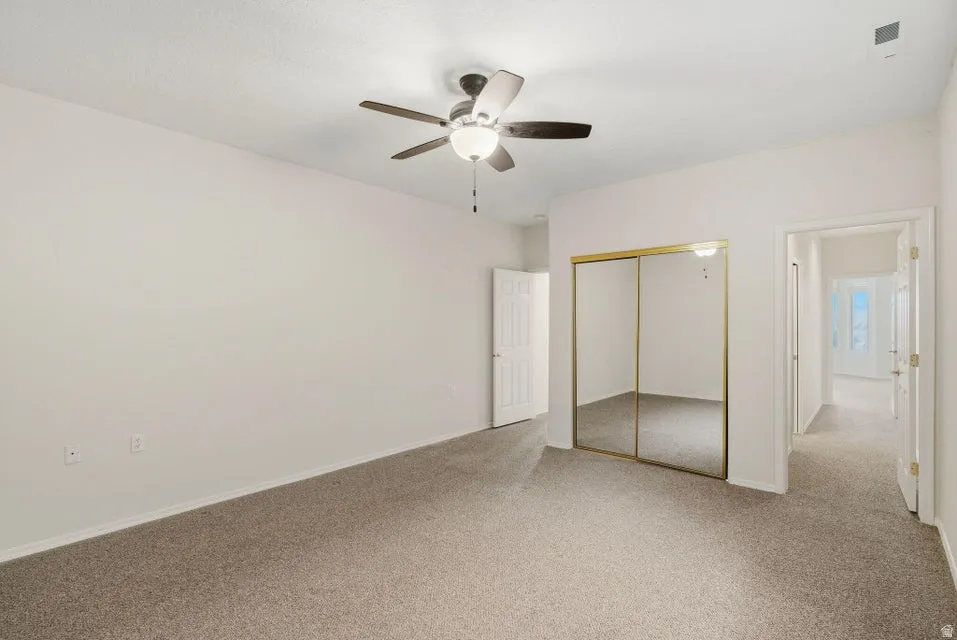 Unfurnished bedroom with a closet, light carpet, and a ceiling fan