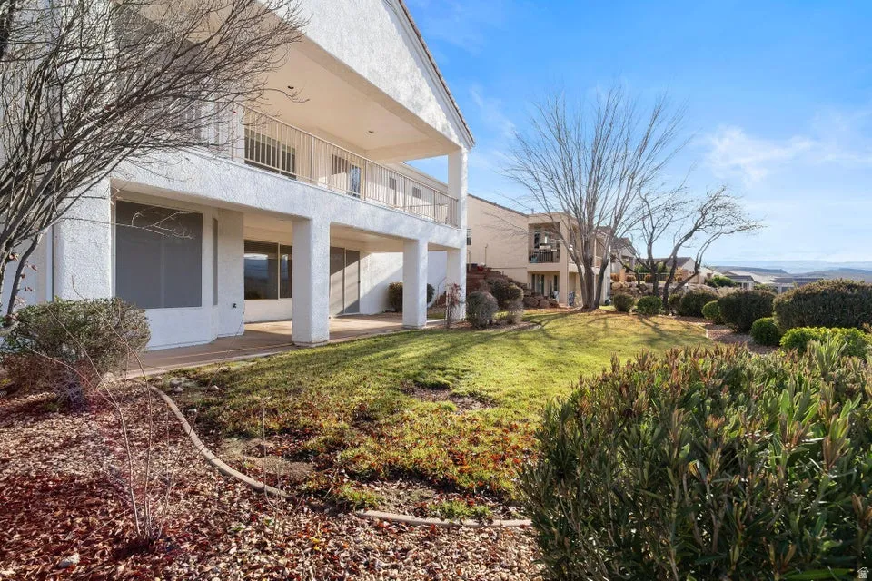 Rear view of property with a balcony, a yard, a patio, and stucco siding