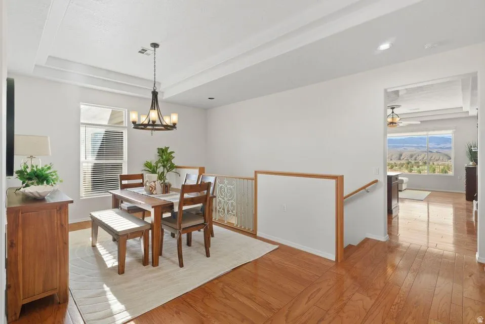 Dining room featuring a tray ceiling, light wood-type flooring, and a chandelier
