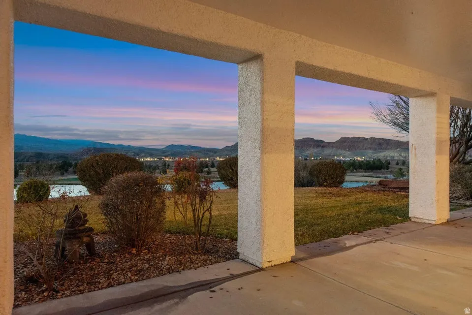 Patio terrace at dusk featuring a mountain view, a patio, and a lawn