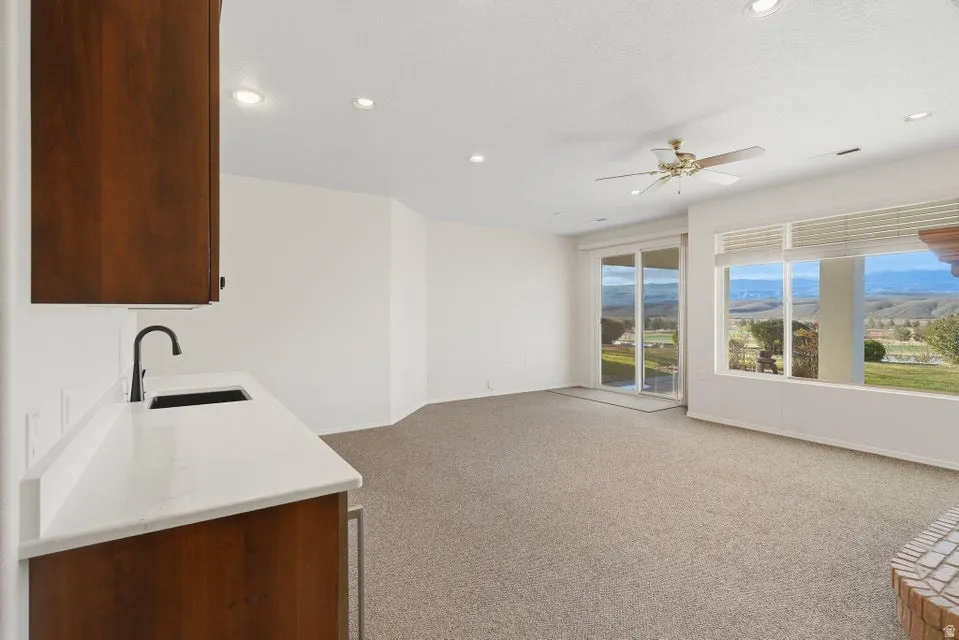 Kitchen featuring light colored carpet, light stone countertops, a mountain view, ceiling fan, and open floor plan