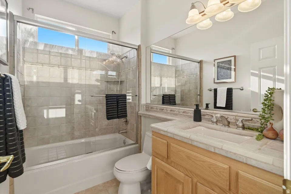 Bathroom with bath / shower combo with glass door, vanity, and plenty of natural light