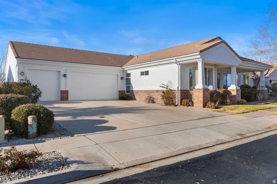 View of front of house with brick siding, concrete driveway, stucco siding, and a tiled roof