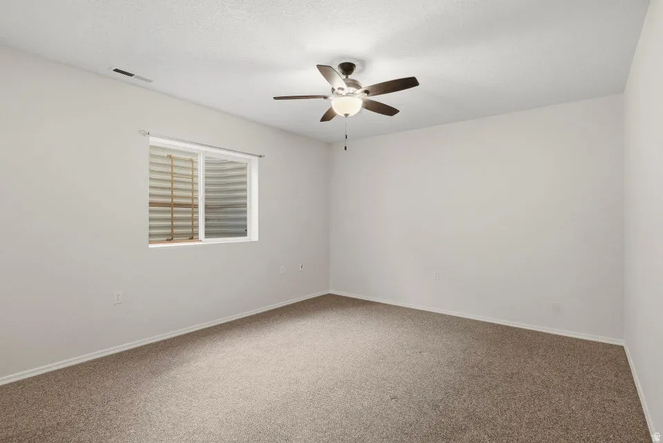 Empty room featuring carpet floors and a ceiling fan
