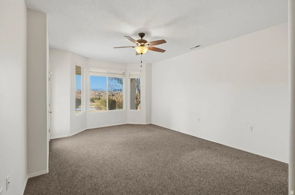 Spare room with carpet flooring, a ceiling fan, and a textured ceiling