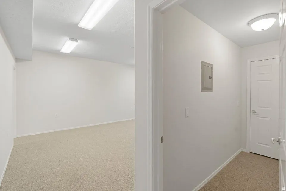 Hall with light colored carpet and electric panel
