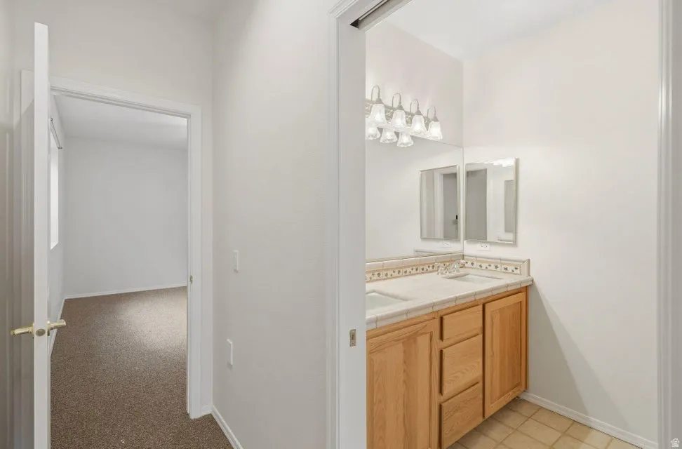 Full bathroom with double vanity and baseboards