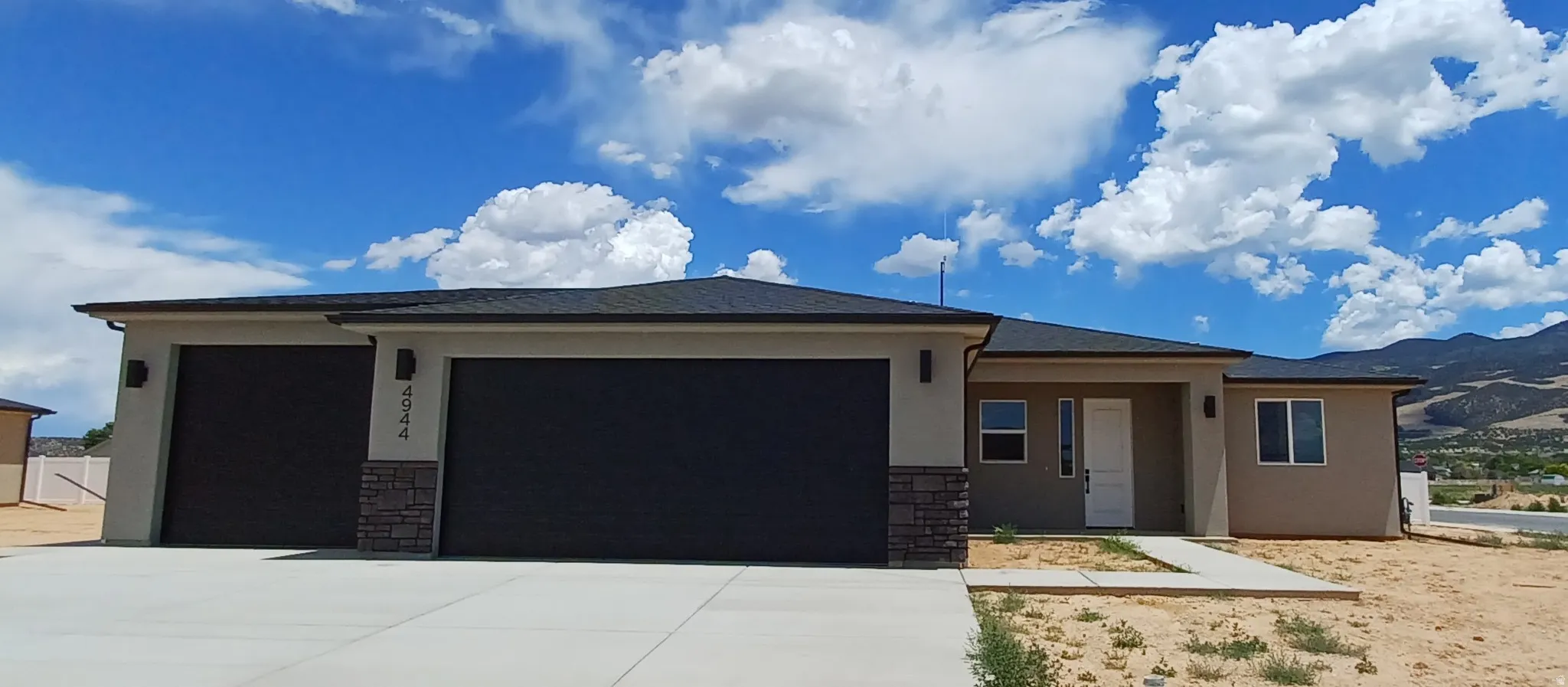 Contemporary single-story residence featuring a neutral stucco exterior, a dark asphalt shingle roof, and a concrete driveway