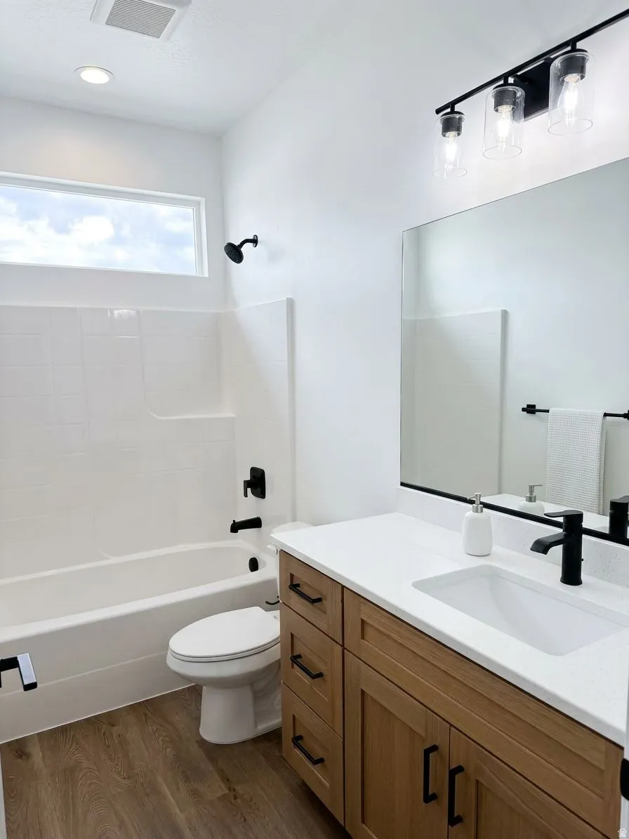 Wood-finish flooring with a white vanity featuring a rectangular sink and matte black faucet