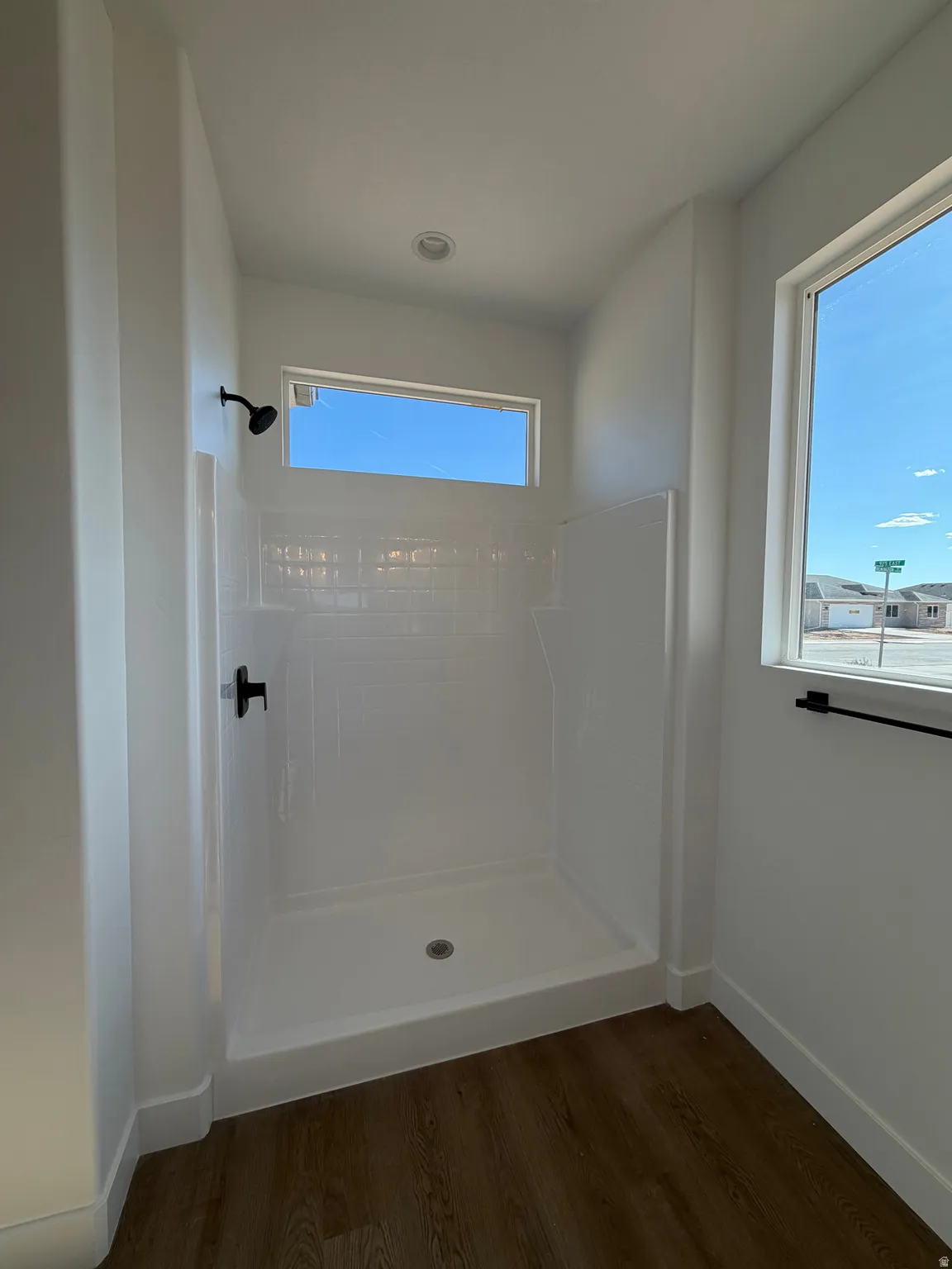 Enclosed shower with white subway tile surround, matte black fixtures, and a transom window