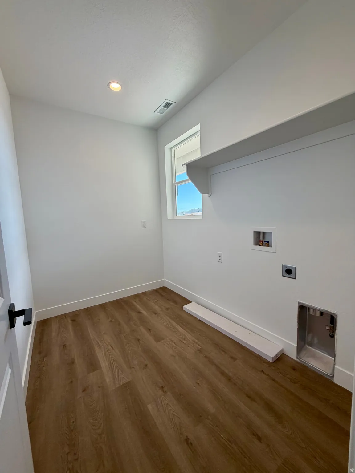 Utility room featuring wood-finish flooring, white walls, and a recessed ceiling light