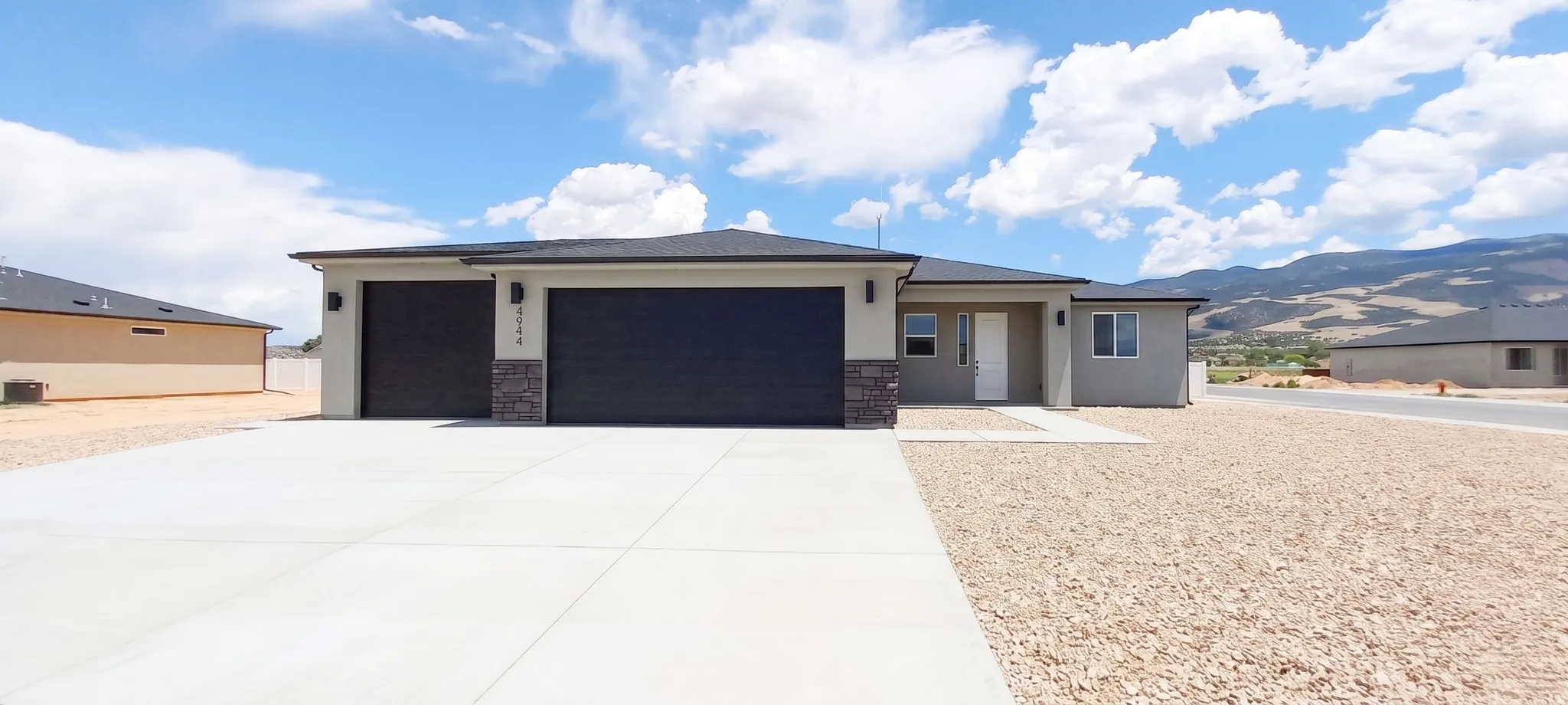 Contemporary exterior with stone accents, a two-car garage, and a concrete driveway