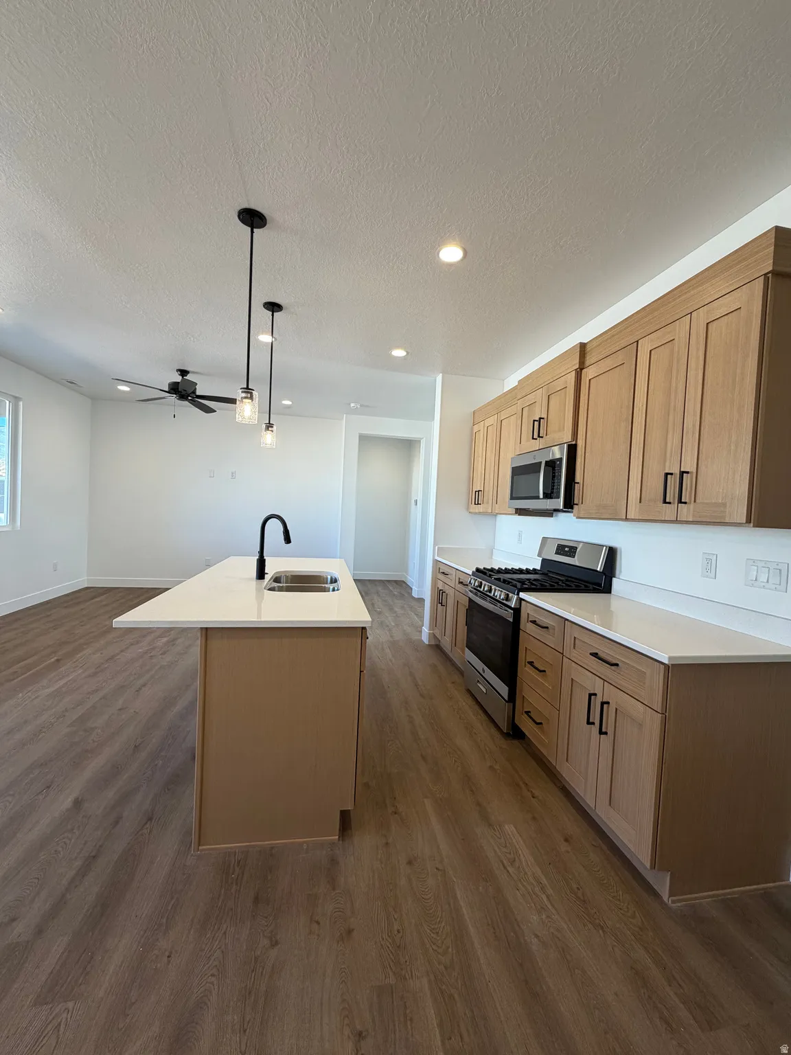 Kitchen island featuring a stainless steel sink, black faucet, and white countertop