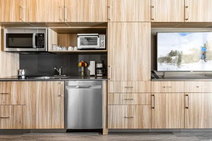 Kitchen featuring modern cabinets, light brown cabinetry, stainless steel appliances, open shelves, and backsplash