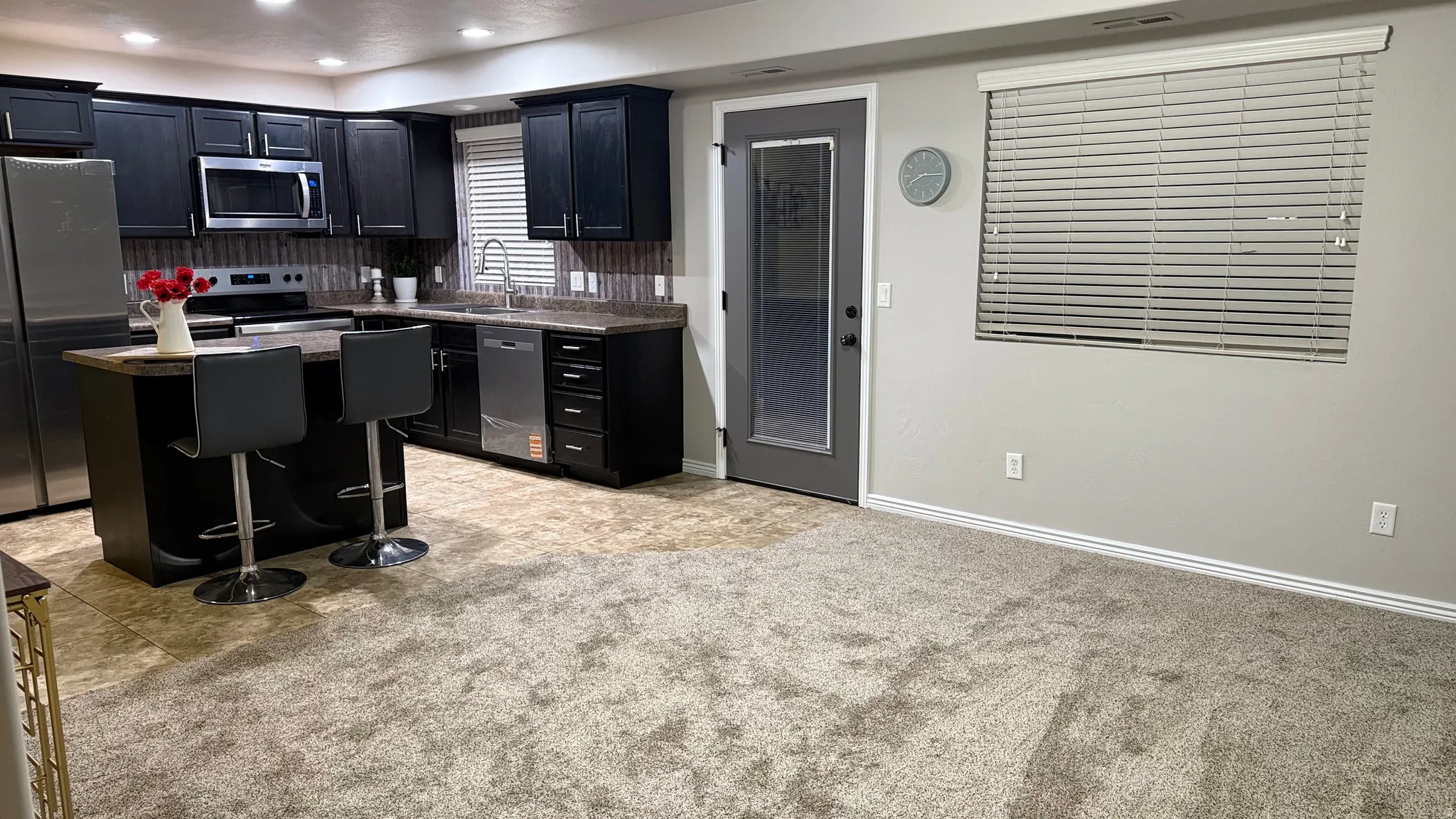 Kitchen with dark cabinets, appliances with stainless steel finishes, dark countertops, a kitchen island, and a breakfast bar