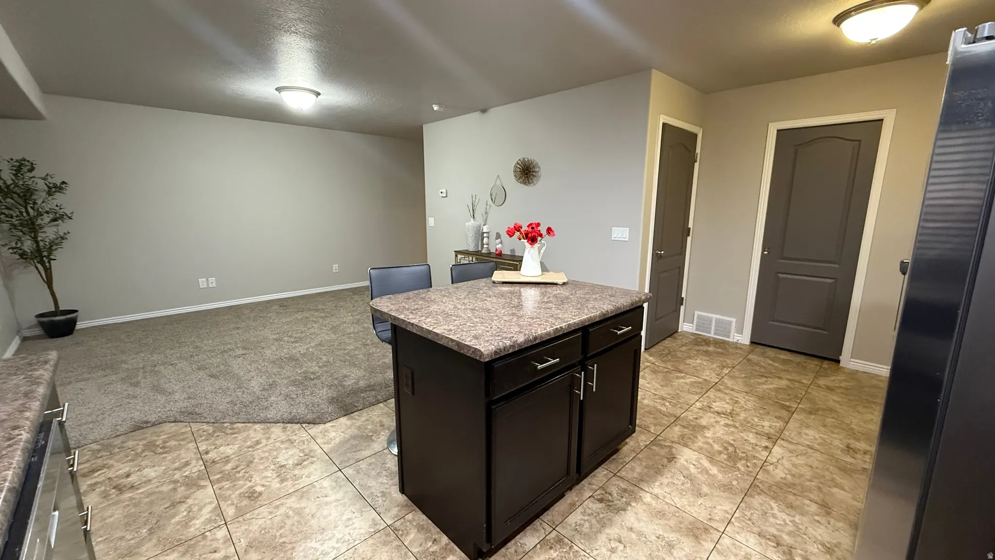 Kitchen with freestanding refrigerator, dark cabinetry, a center island, a breakfast bar, and open floor plan