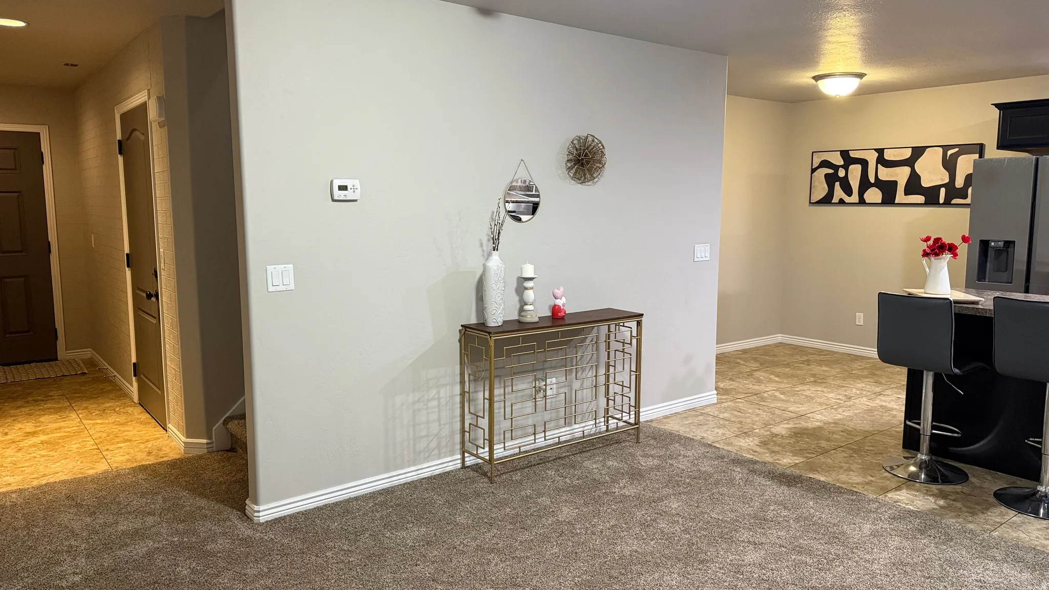 Corridor featuring light tile patterned flooring and light colored carpet