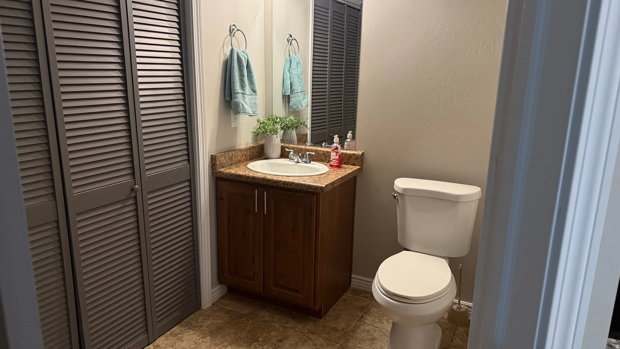 Half bath featuring a closet, vanity, and a textured wall
