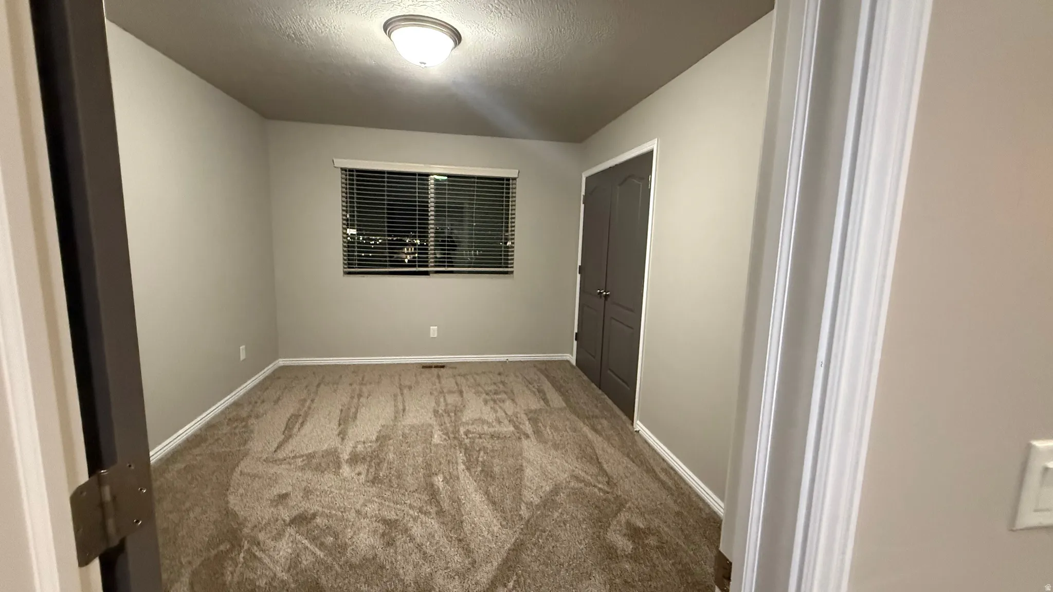 Empty room with carpet and a textured ceiling