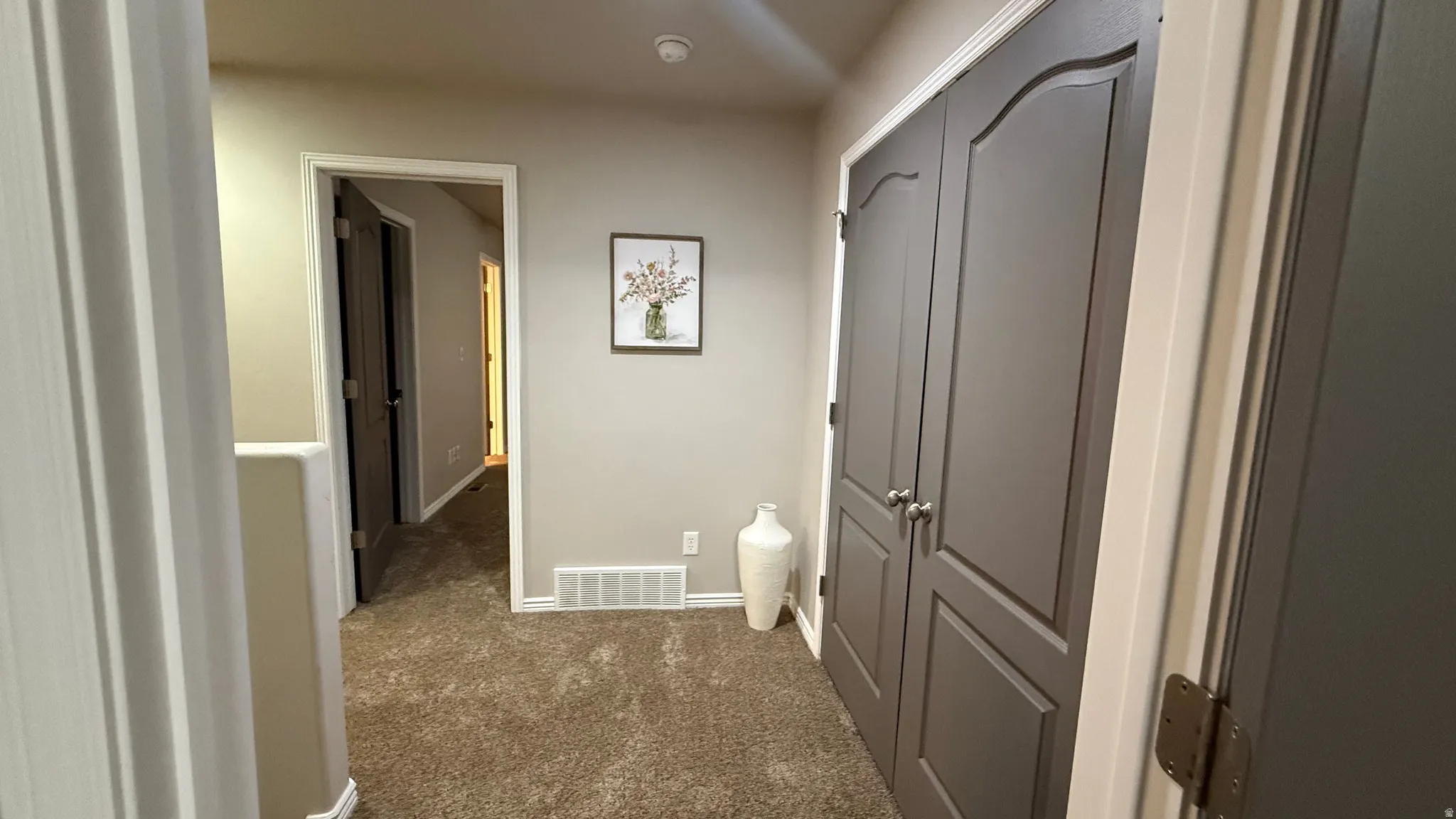 Hallway with dark colored carpet and baseboards