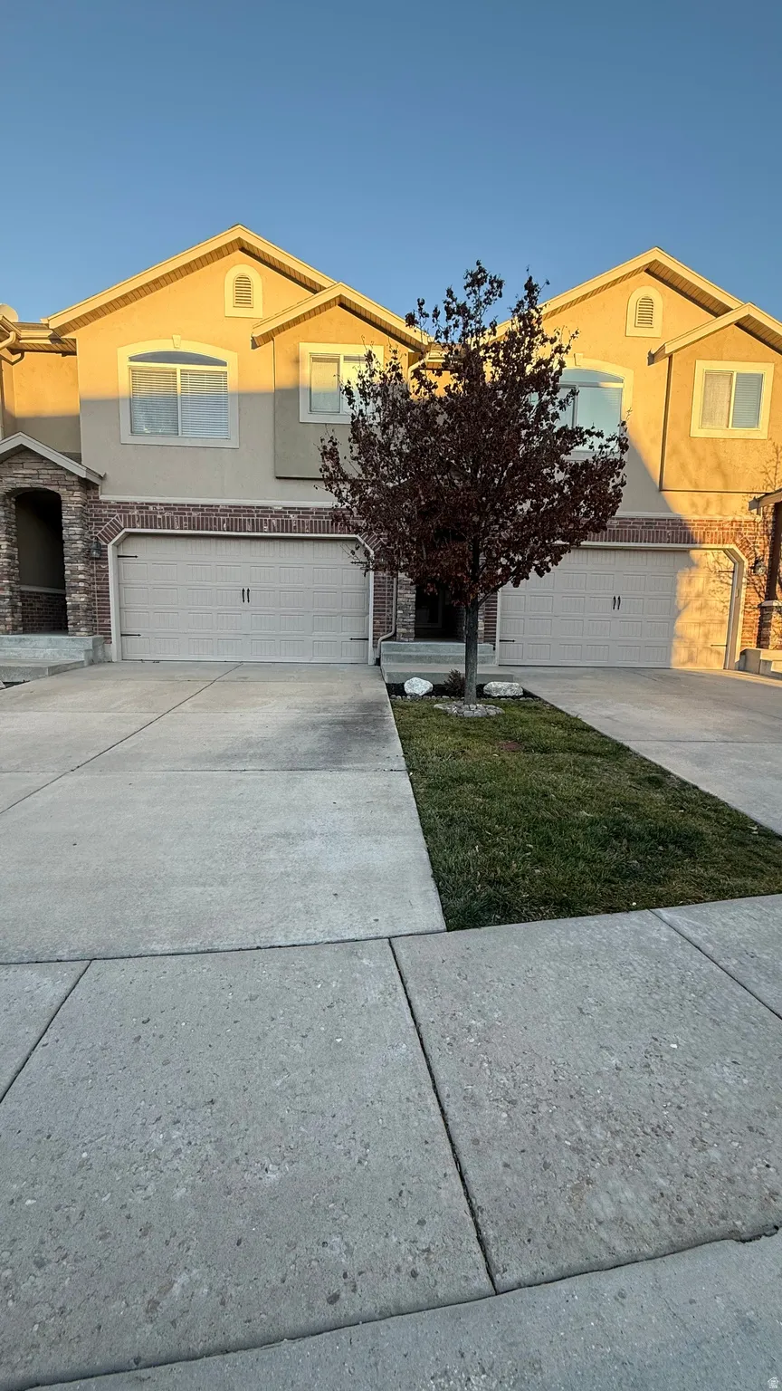 View of front of property with concrete driveway, stucco siding, stone siding, and a garage