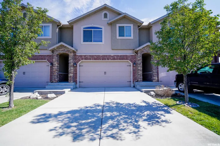 Traditional-style home featuring stucco siding, concrete driveway, and stone siding