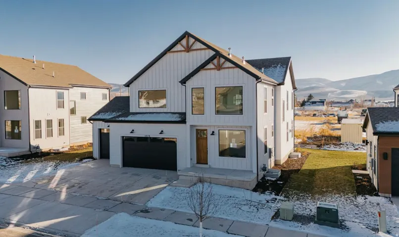 Modern farmhouse featuring a mountain view, board and batten siding, a garage, driveway, and roof with shingles