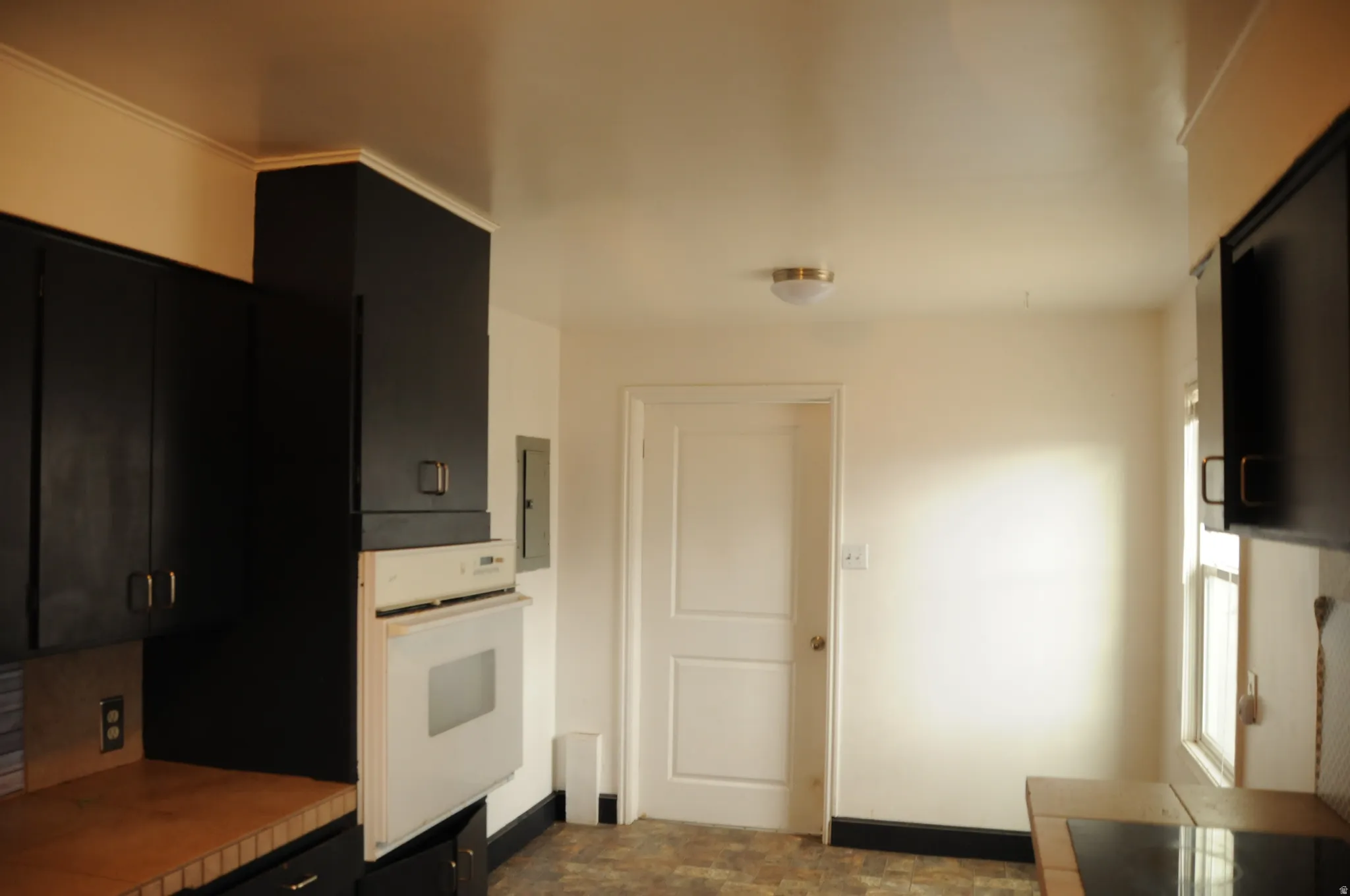 Kitchen featuring dark cabinetry, white oven, light countertops, stone finish flooring, and stovetop