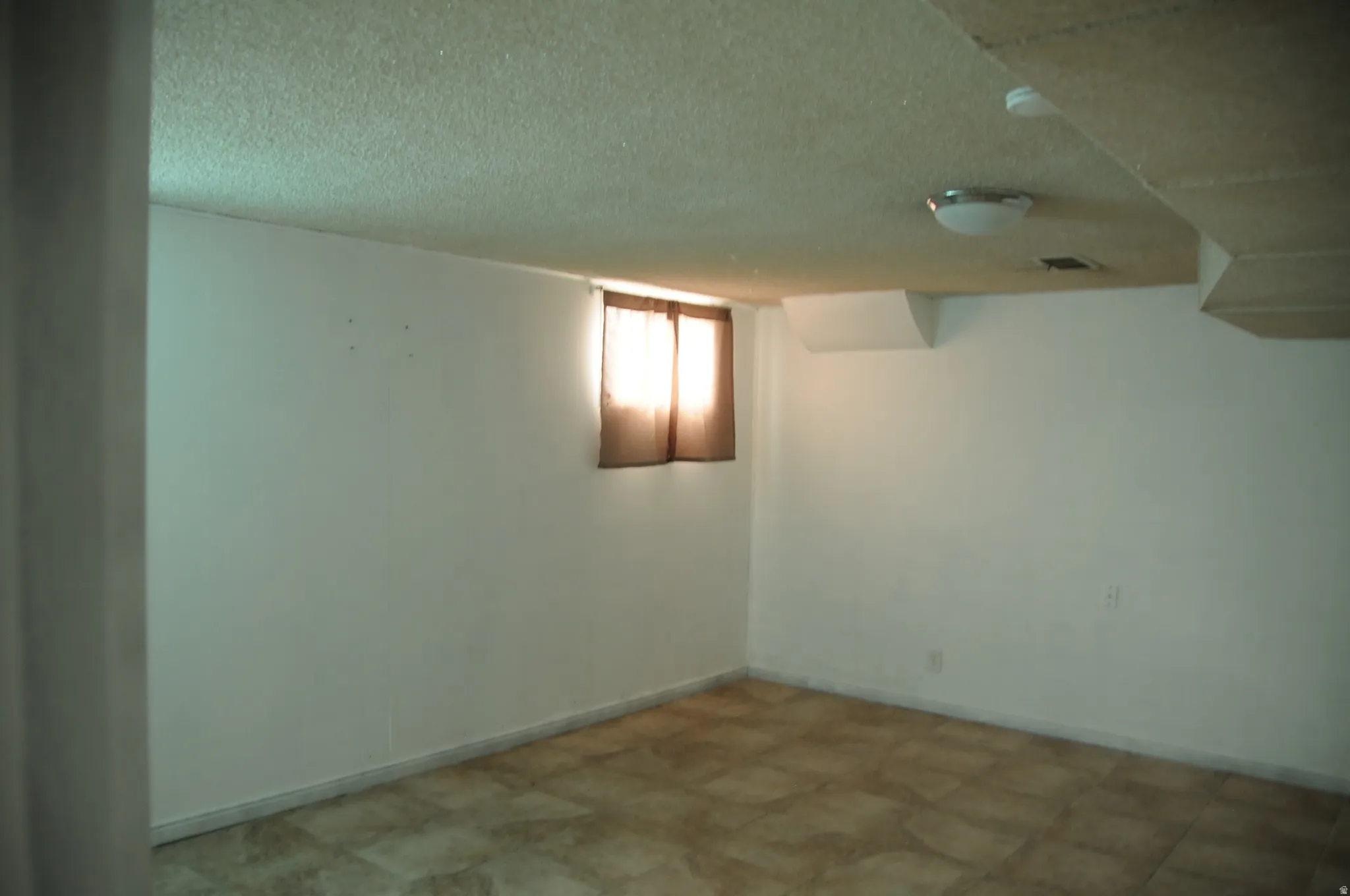 Basement with a textured ceiling and tile patterned floors