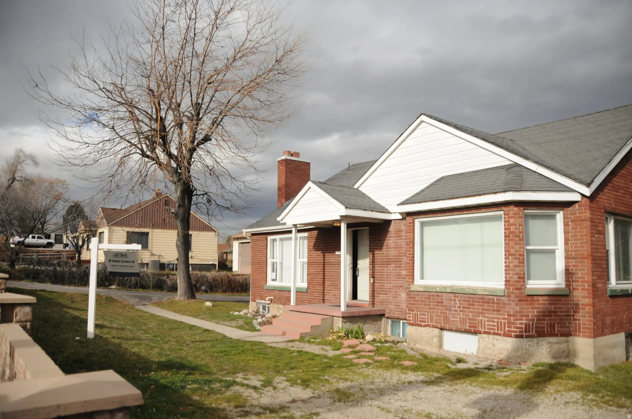View of front of home featuring a chimney, a front lawn, brick siding, and a shingled roof